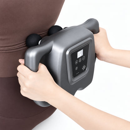 Person using a handheld massage device on their arm with a neutral background